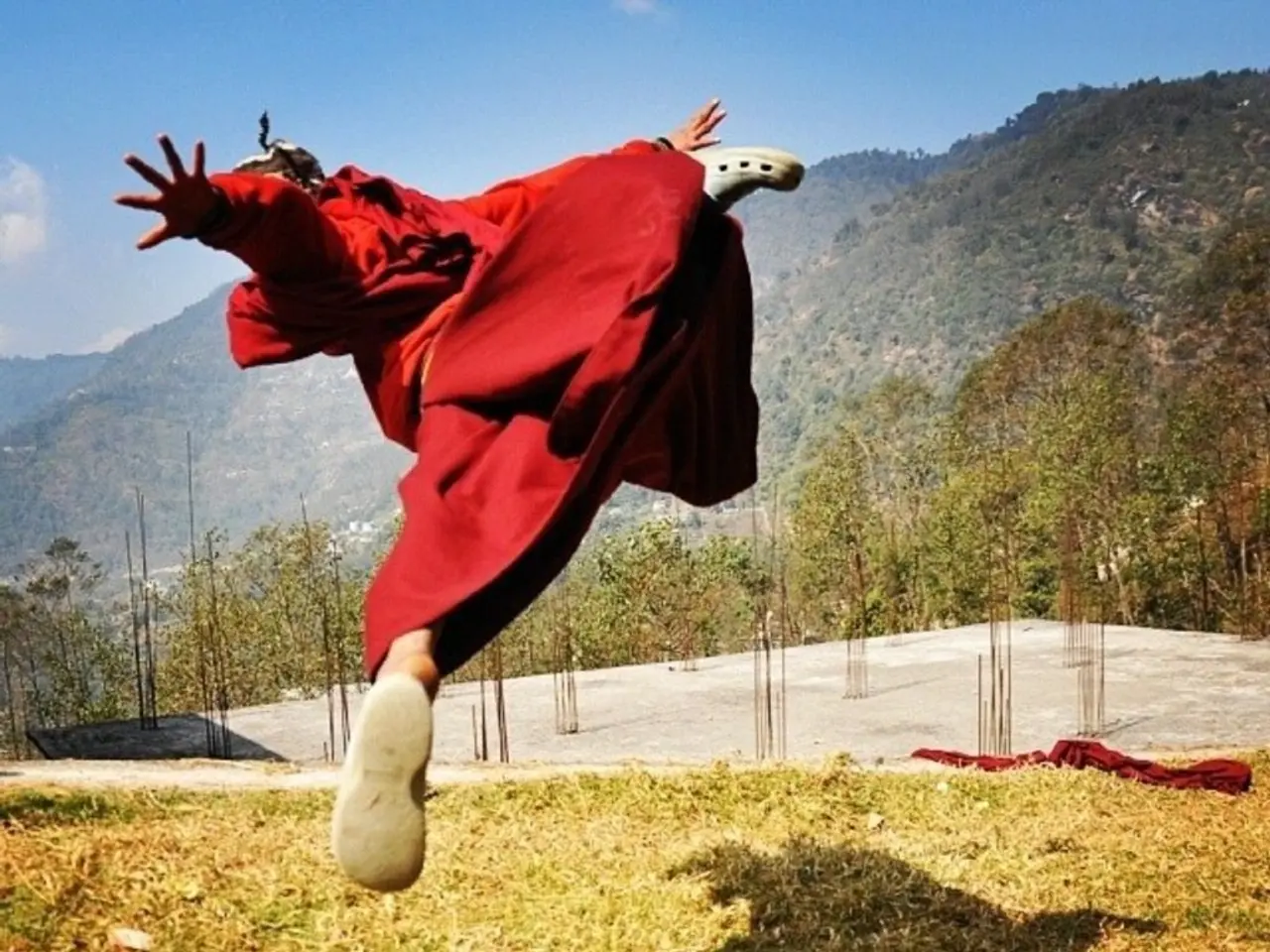 This is a person jumping. This person wore a red dress and shoes. This is the grass. I can see the...
