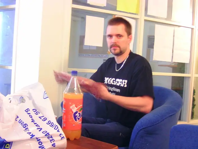 In the image we can see there is a man who is sitting on a blue chair and in front of him there is...