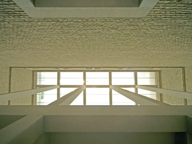 In this image there are pillars attached to the glass roof. Background there is a wall.