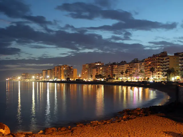 In the image there is a sea and around the sea there are many tall buildings, trees, street lights...