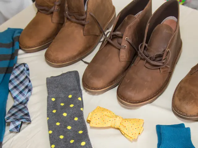 In this picture we can see a bow tie, socks, shoes and these all are placed on a white cloth.